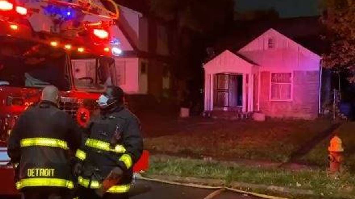 House after a fire has been put out. A fire truck with lights on and a fireman can be seen out front.