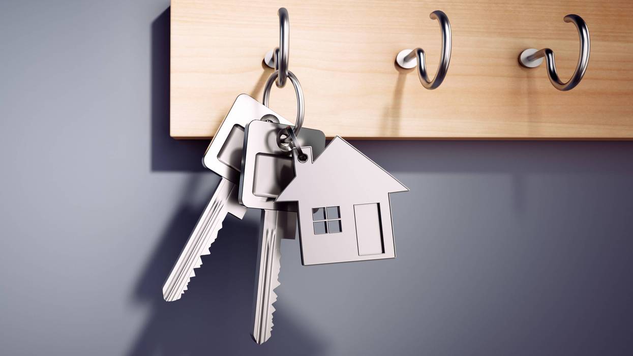 House keys with key ring hanging on wooden board