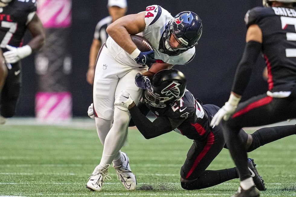 Houston Texans tight end Teagan Quitoriano (84) is tackled by Atlanta Falcons safety Richie Grant (27) at Mercedes-Benz Stadium.