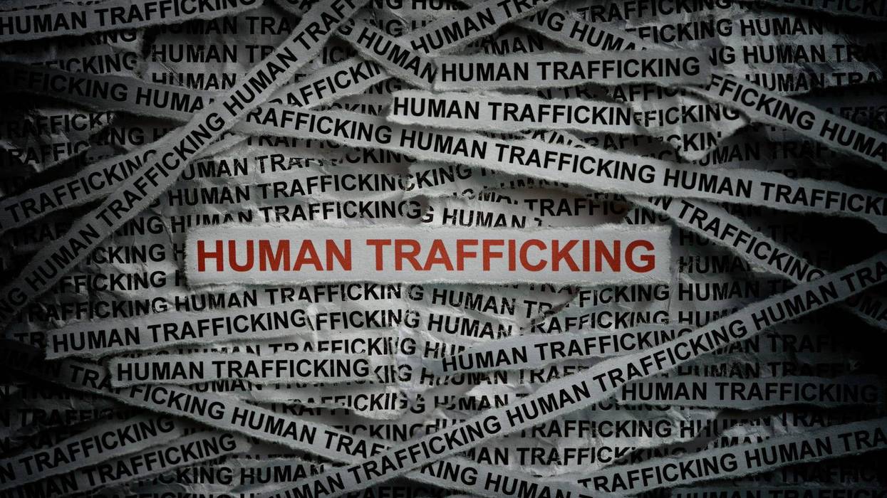 Human Trafficking graphic showing the word on small strips of paper. Most are in black and white. One, front and center, is in red.