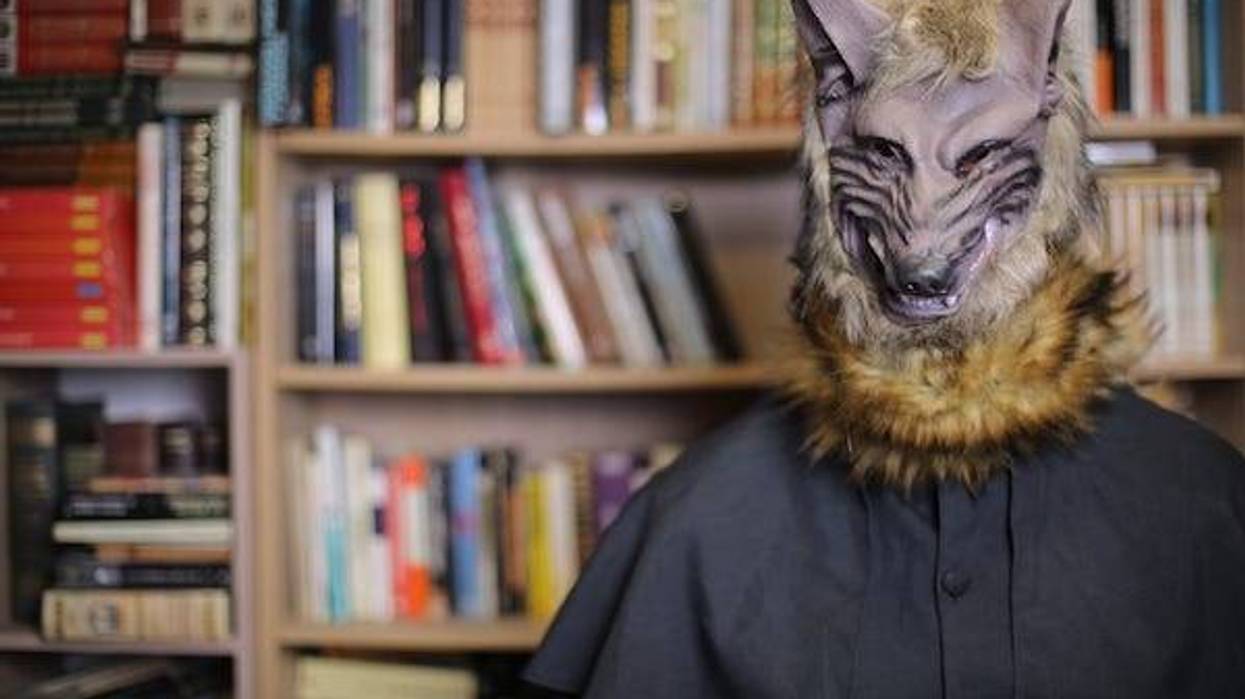 Human wearing spooky wolf mask with library in the background