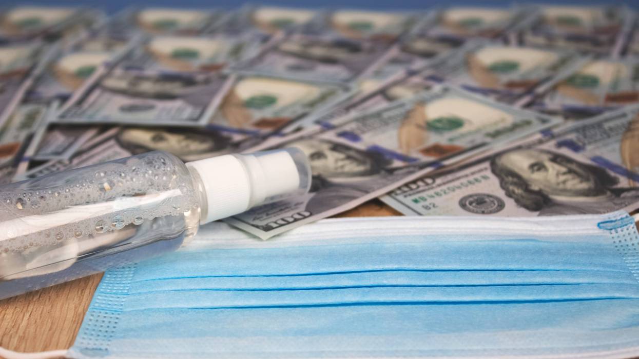 hundred dollar bills with mask and hand sanitizer