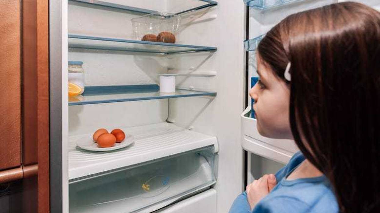 hungry girl looking into empty fridge