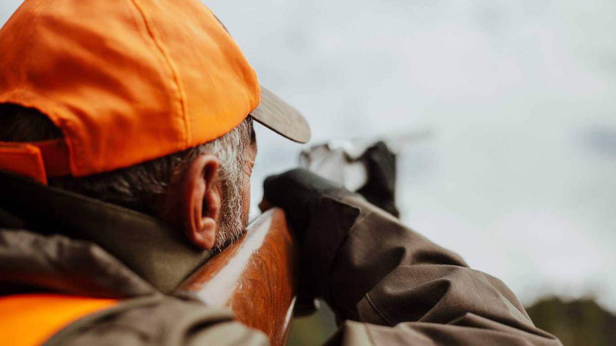 Hunter raising his firearm.