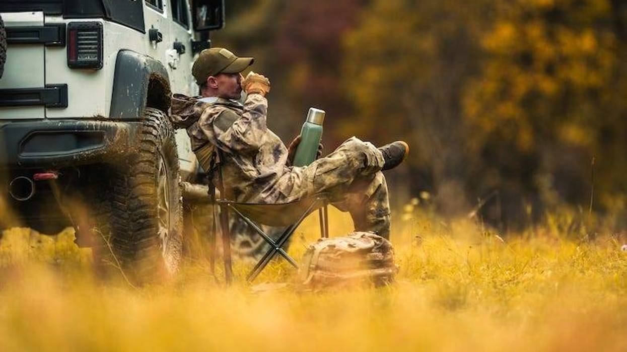 Hunter sitting next to his vehicle drinking coffee