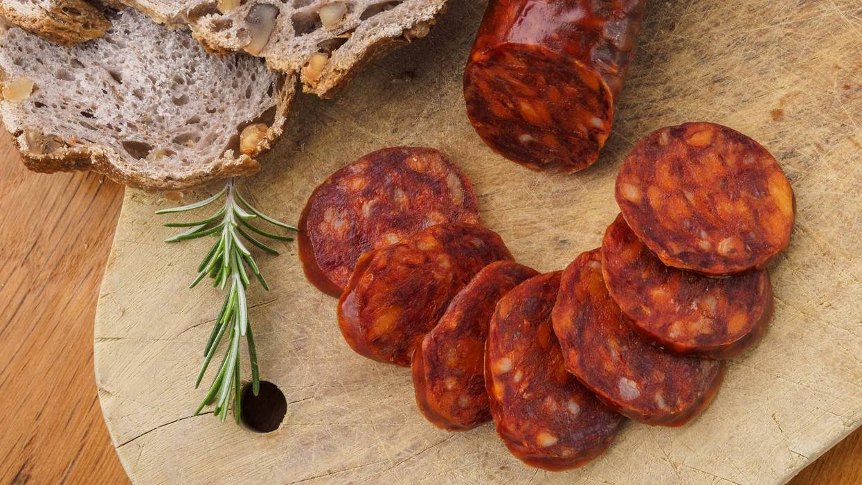 Iberian chorizo, Spanish chorizo or Spanish sausage cut into slices on a wooden board with rustic bread.