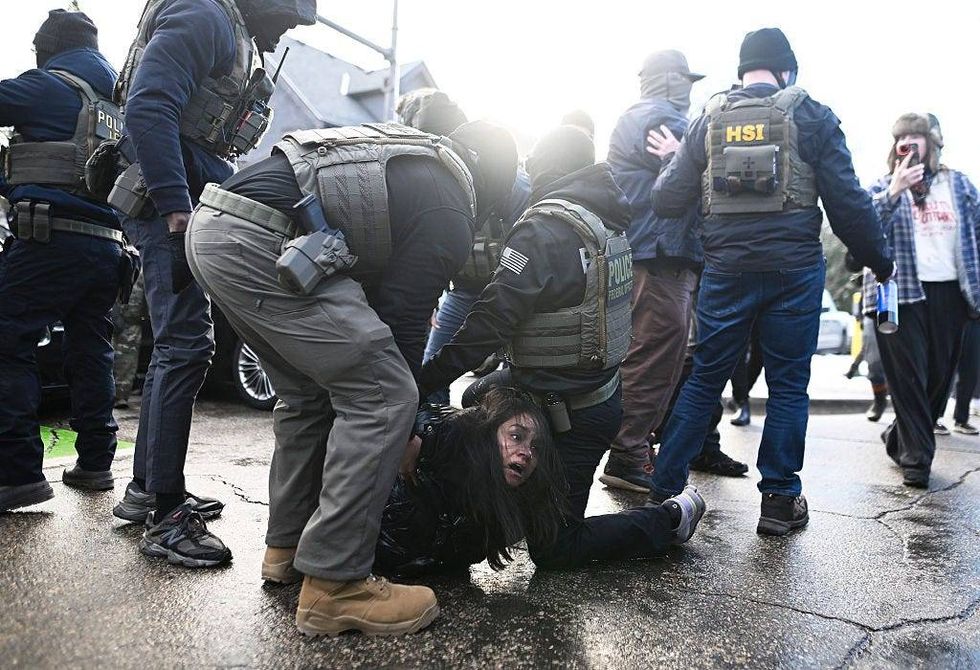 ICE agents detain a woman after pulling her from a car before on January 13, 2026 in Minneapolis, Minnesota.