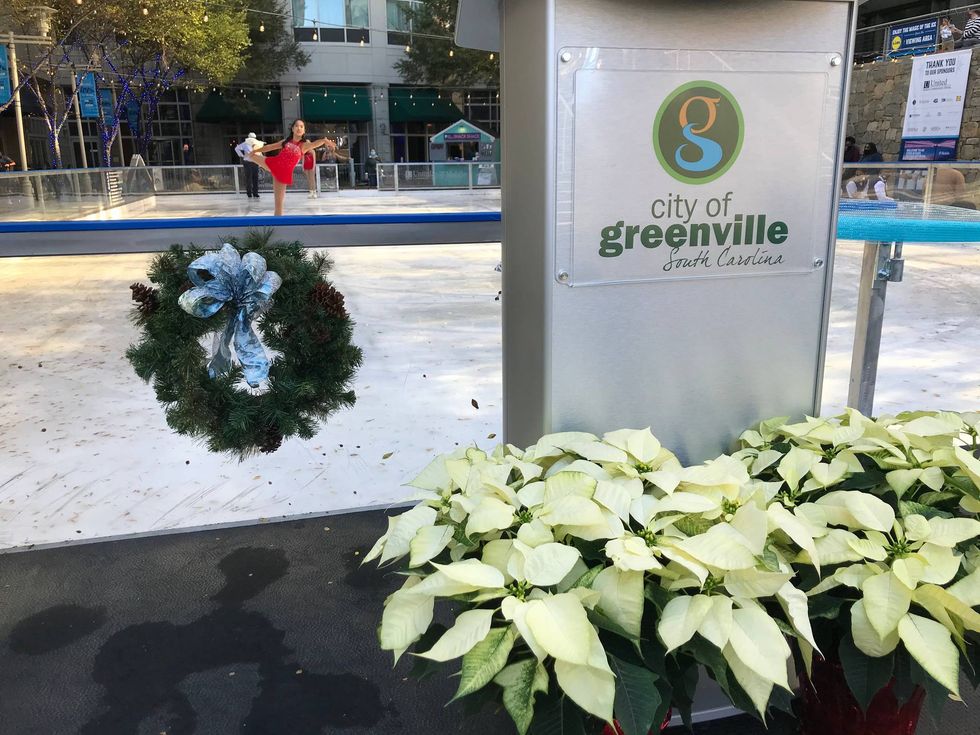 Ice skater performs before the opening as the podium for the speakers stands front and center with white poinsettias