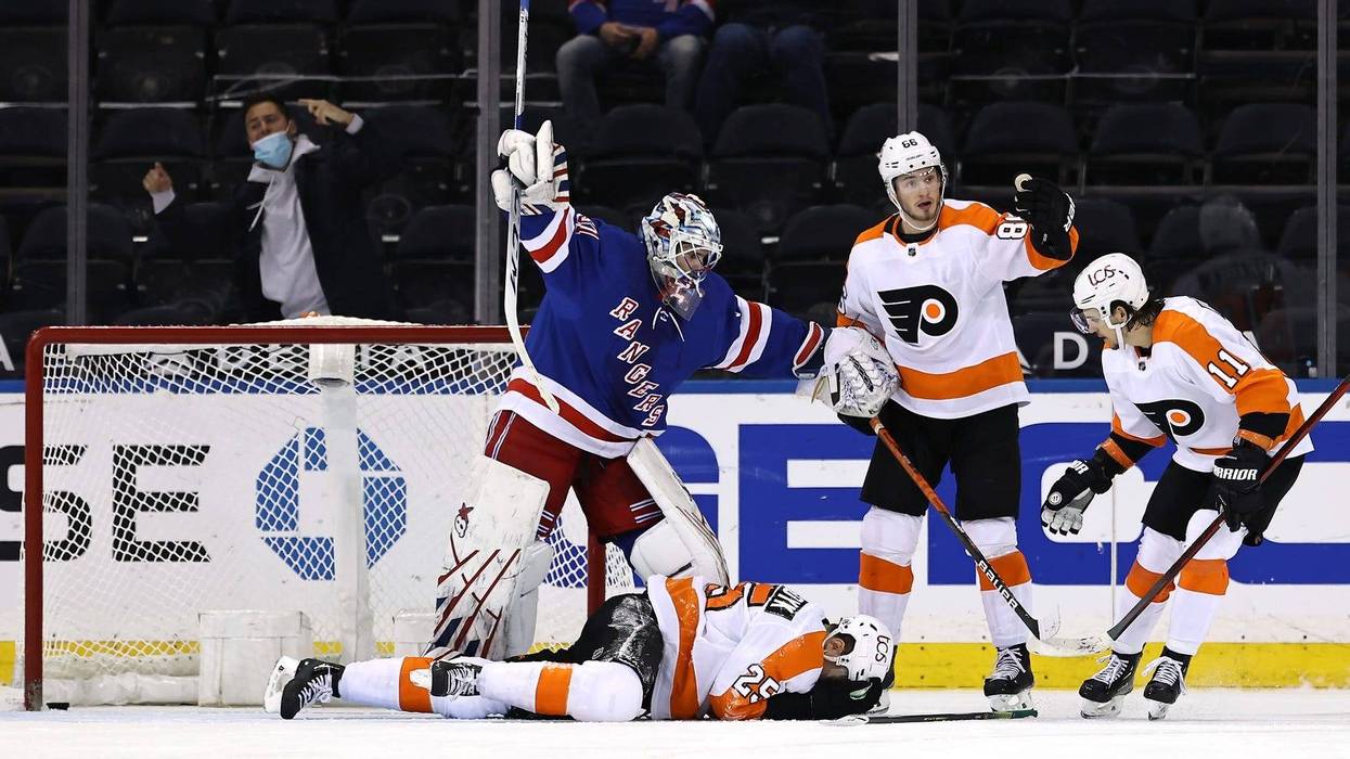 Igor Shesterkin of the New York Rangers signals for help after James van Riemsdyk of the Philadelphia Flyers falls to the ice after a puck went into the net off of his face.