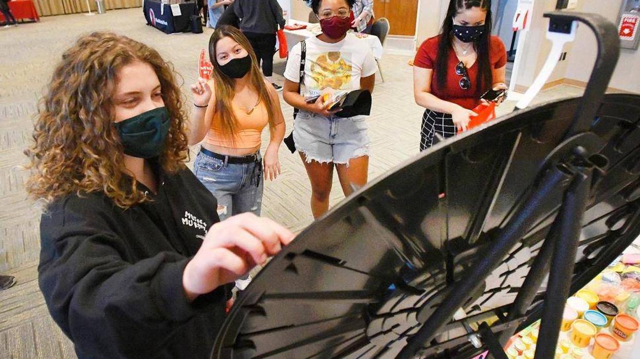 Illinois State University students Rhiannon Pschirrer, left, Jasminh Randall, Alexis Robles and Michaela Dennis try out there hand on a wheel of fortune as they participate in the school's alternative spring break giveaways at Bone Student Center in Normal, Ill., Tuesday, March 9, 2021.