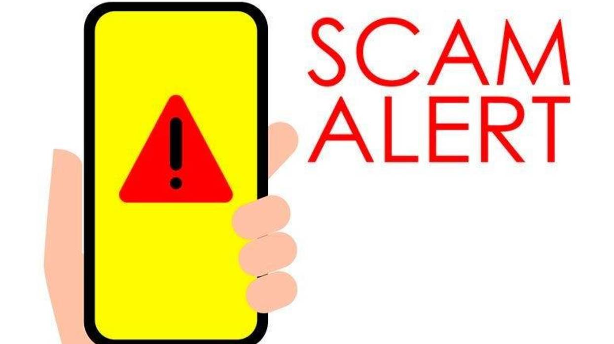 Illustration of Scam Alert Hand holding a mobile phone with scam alert sign