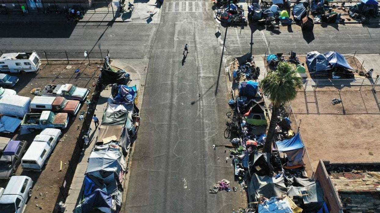 In an aerial view, people walk through a section of the 'The Zone', Phoenix's largest homeless encampment, amid the city's worst heat wave on record on July 26, 2023 in Phoenix, Arizona. While Phoenix endures periods of extreme heat every year, today marked the 27th straight day of temperatures reaching 110 degrees or higher, a new record amid a long duration heat wave in the Southwest. Extreme heat kills more people than hurricanes, floods and tornadoes combined in an average year in the U.S. Unhoused people are at an especially high risk of heat-related illness or death. (Photo by Mario Tama/Getty Images)