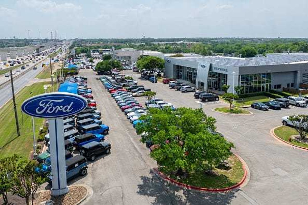 In an aerial view, vehicles are seen for sale on a lot at a dealership on April 18, 2025 in Austin, Texas.