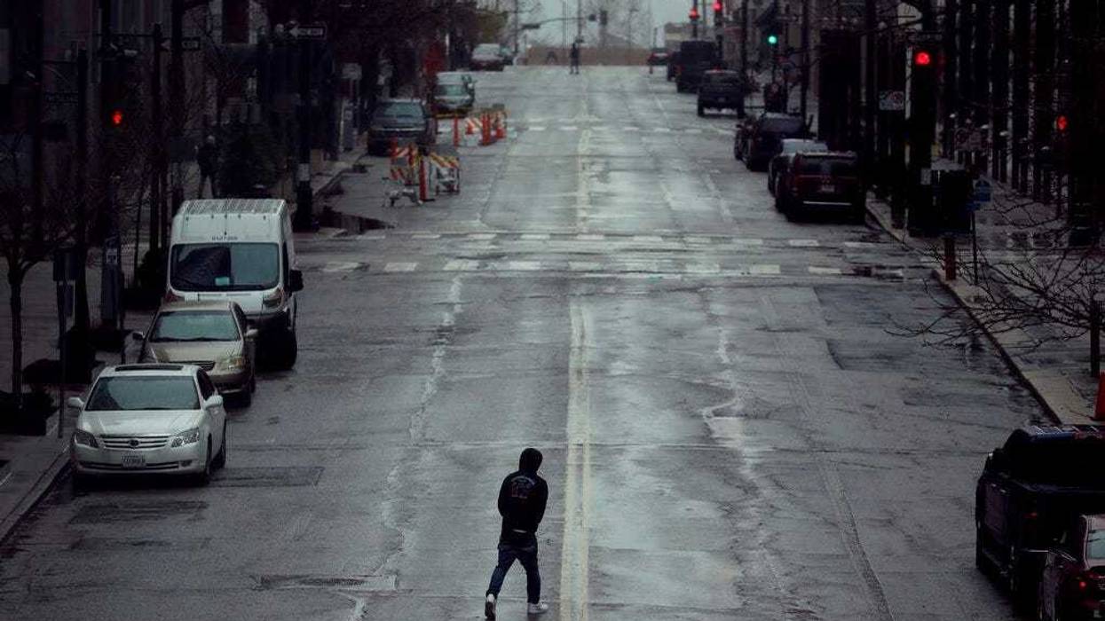 In this April 3, 2020, file photo a man crosses an empty street in downtown Kansas City, Mo. (AP Photo/Charlie Riedel, File)