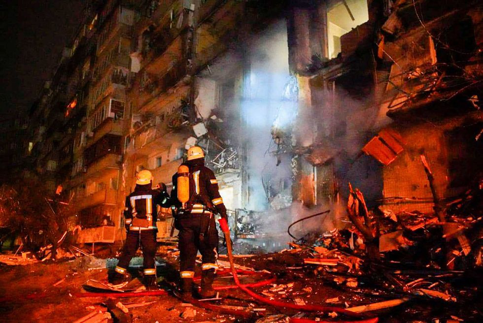 In this handout photo taken from video released by Ukrainian Police Department Press Service released on Friday, Feb. 25, 2022, firefighters inspect the damage at a building following a rocket attack on the city of Kyiv, Ukraine