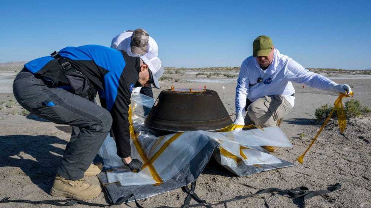 In this handout provided by NASA, from left to right, Lockheed Martin Mission Operations Assurance Lead Graham Miller, Lockheed Martin Recovery Specialist Michael Kaye, and Lockheed Martin Recovery Specialist Levi Hanish prepare the sample return capsule from NASA's OSIRIS-REx mission for transport shortly after the capsule landed at the Department of Defense's Utah Test and Training Range, on September 24, 2023 at the Department of Defense's Utah Test and Training Range in Dugway, Utah.