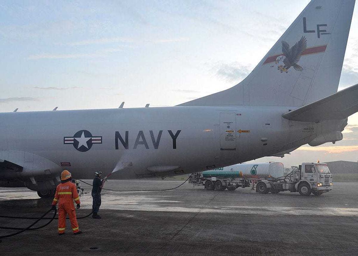 In this handout provided by the U.S. Navy, Aviation Structural Mechanic 2nd Class Matthew Walton, assigned to Patrol Squadron (VP) 16, sprays down a P-8A Poseidon with fresh water on March 18, 2014 in Kuala Lumpur, Malaysia.
