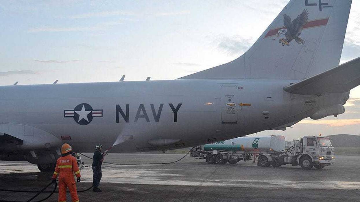 In this handout provided by the U.S. Navy, Aviation Structural Mechanic 2nd Class Matthew Walton, assigned to Patrol Squadron (VP) 16, sprays down a P-8A Poseidon with fresh water on March 18, 2014 in Kuala Lumpur, Malaysia.