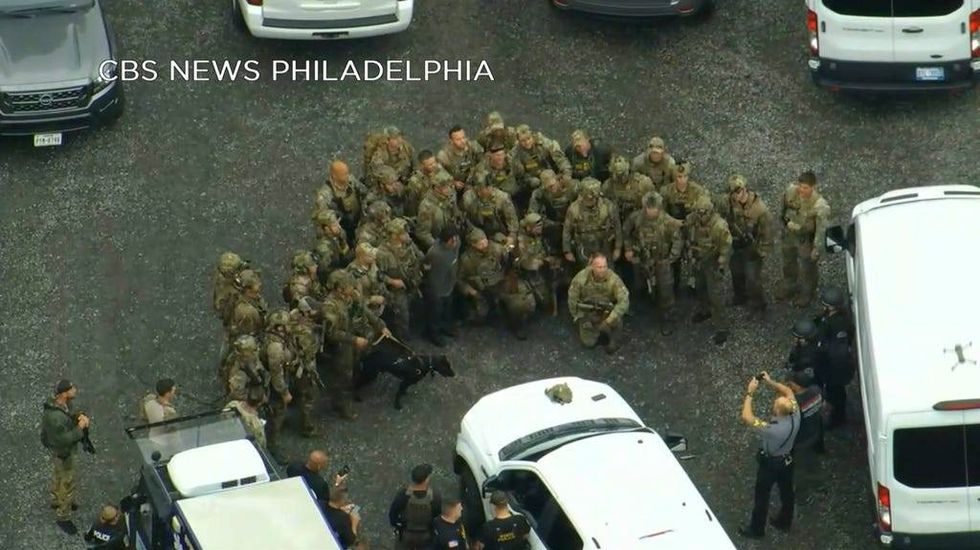 In this image from video provided by CBS News Philadelphia, law enforcement officers pose for a group photo with Danelo Cavalcante after his capture in Chester County.