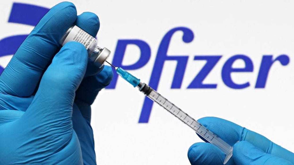 In this photo illustration, a medical syringe and vials of the Pfizer US pharmaceutical corporation and BioNTech German biotechnology 2021 company logos are seen on October 03, 2021 in New York City.