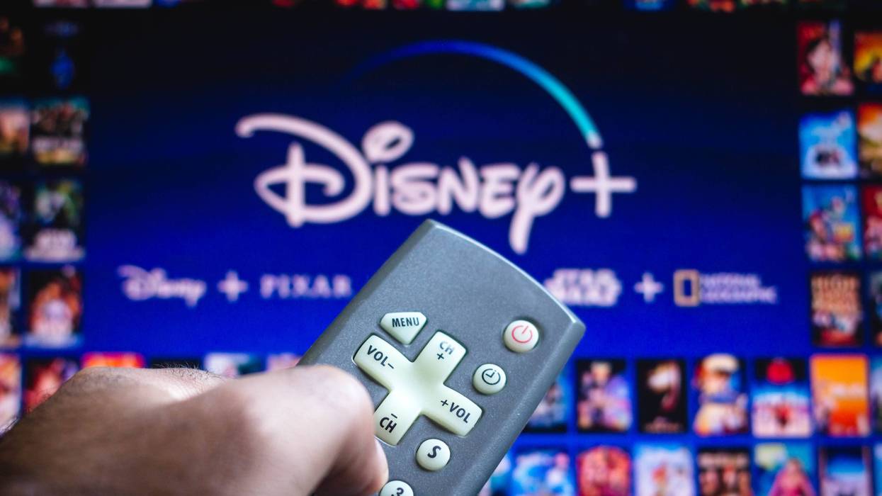 In this photo illustration a person holding a TV remote control and the Disney+ (Plus) logo in the background. (Photo by Rafael Henrique / SOPA Images/Sipa USA)