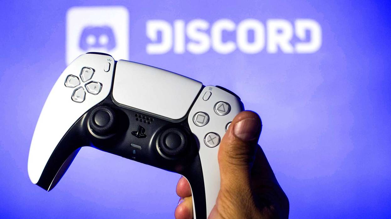 In this photo illustration, a PlayStation 5 controller seen with a Discord logo in the background.