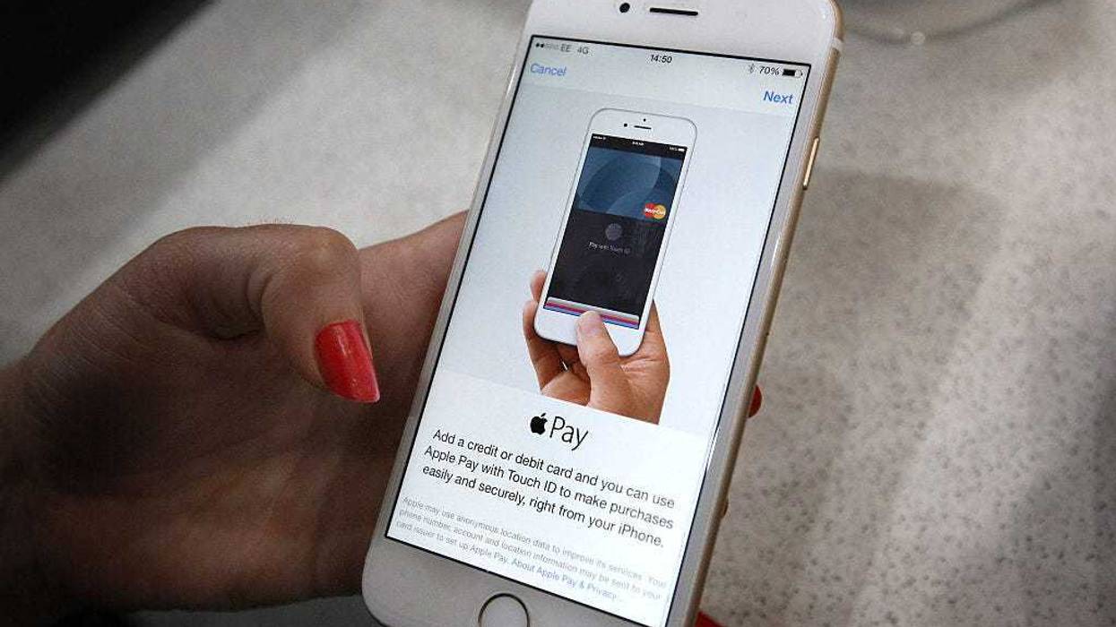 In this photo illustration, an iPhone is used to make an Apple Pay purchase at The Post Office on July 14, 2015 in London, England.