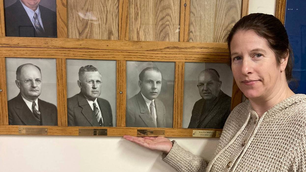 In this photo provided by Dan Donaldson, Dana Klabenes, the city clerk in Neligh, Neb., holds her hand under a photo of former Mayor Fred Benning, a World War I veteran who is being honored by having an Army base in Georgia renamed Fort Benning in his honor, at city hall on Tuesday, March 4, 2025.