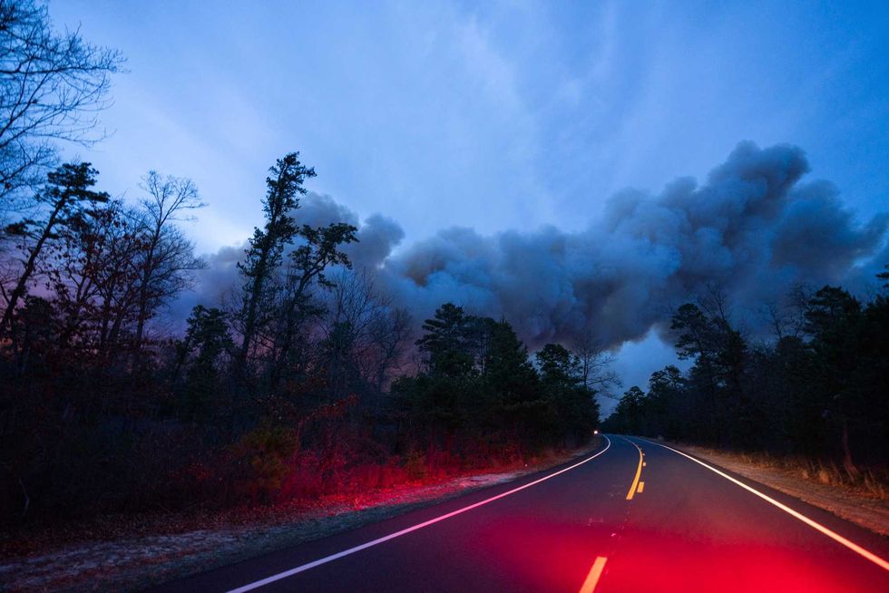 In this photo provided by the New Jersey Department of Environmental Protection, a massive 2,500-acre forest fire burns in Ocean County, N.J., early Wednesday, April 12, 2023, as firefighters battle the blaze