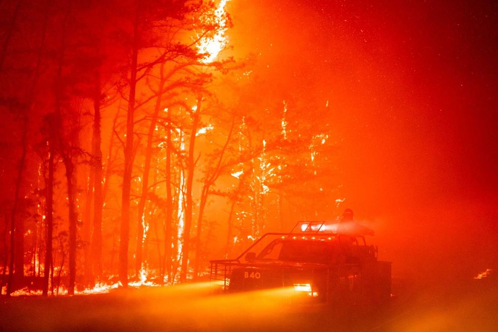 In this photo provided by the New Jersey Department of Environmental Protection, a massive 2,500-acre forest fire burns in Ocean County, N.J., early Wednesday, April 12, 2023, as firefighters battle the blaze