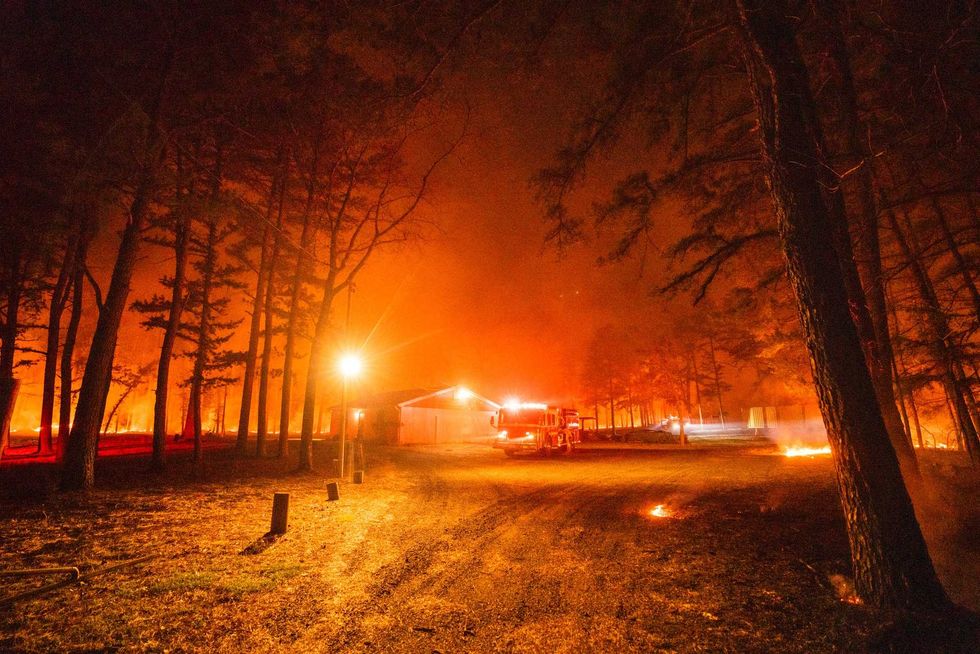 In this photo provided by the New Jersey Department of Environmental Protection, a massive 2,500-acre forest fire burns in Ocean County, N.J., early Wednesday, April 12, 2023, as firefighters battle the blaze