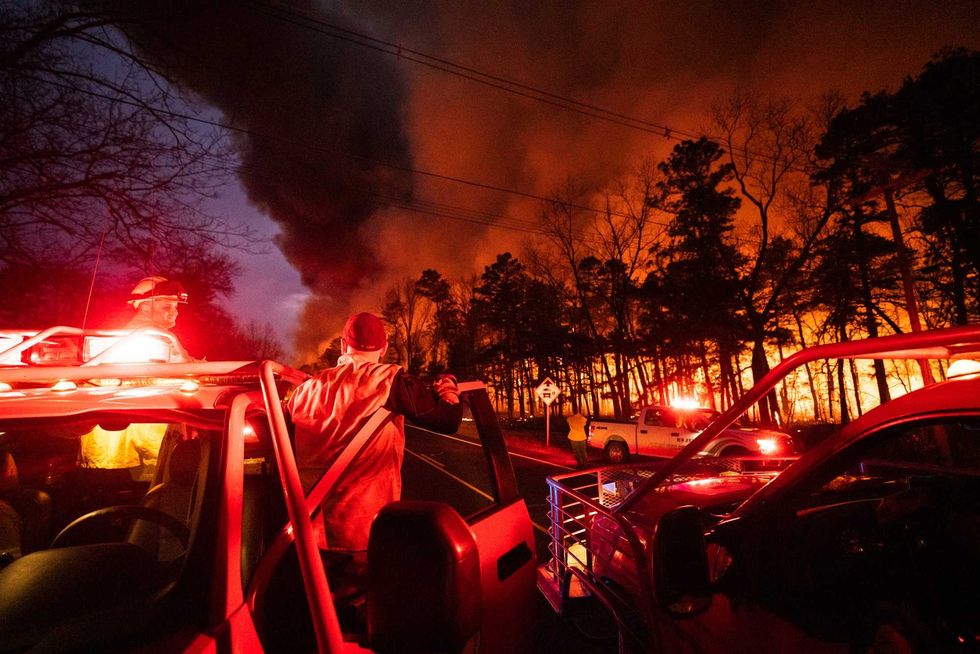 In this photo provided by the New Jersey Department of Environmental Protection, a massive 2,500-acre forest fire burns in Ocean County, N.J., early Wednesday, April 12, 2023, as firefighters battle the blaze