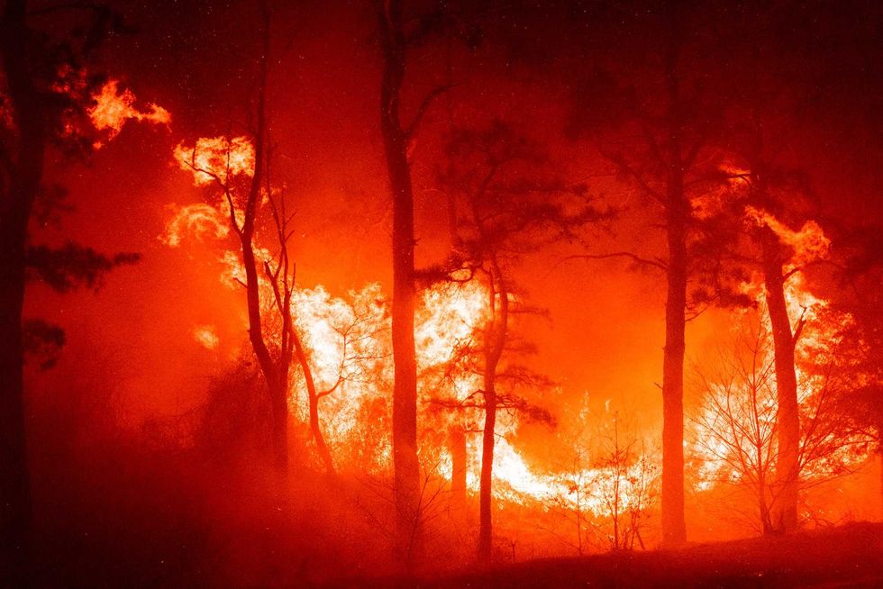 In this photo provided by the New Jersey Department of Environmental Protection, a massive 2,500-acre forest fire burns in Ocean County, N.J., early Wednesday, April 12, 2023, as firefighters battle the blaze