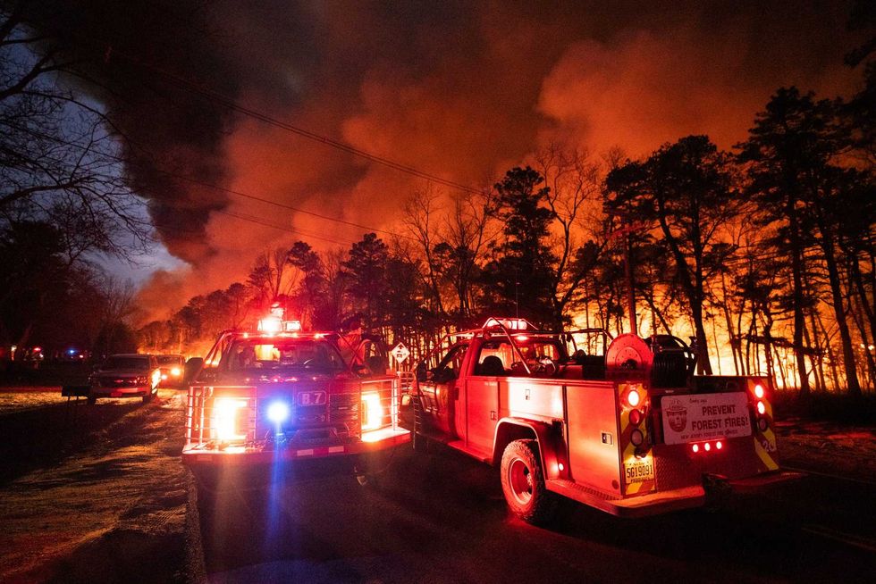 In this photo provided by the New Jersey Department of Environmental Protection, a massive 2,500-acre forest fire burns in Ocean County, N.J., early Wednesday, April 12, 2023, as firefighters battle the blaze