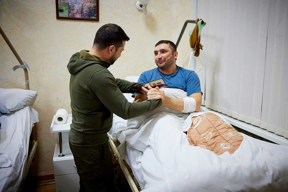 In this photo provided by the Ukrainian Presidential Press Office on Sunday, March 13, 2022, President Volodymyr Zelenskyy awards a state medal to a wounded soldier during his visit to a hospital in Kyiv, Ukraine