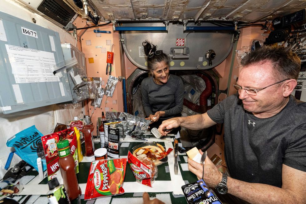 In this photo released by NASA, astronauts Suni Williams and Butch Wilmore, both Expedition 71 Flight Engineers, make pizza aboard the International Space Station
