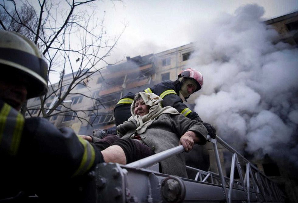 In this photo released by Ukrainian State Emergency Service press service, firefighters evacuate an elderly woman from an apartment building hit by shelling in Kyiv, Ukraine, Monday, March 14, 2022