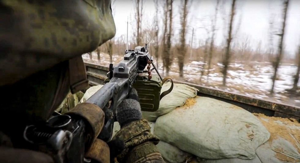 In this photo taken from video released by the Russian Defense Ministry Press Service on Thursday, March 3, 2022, a Russian soldier points a gun from a Russian military truck as it drives through an undisclosed location in Ukraine
