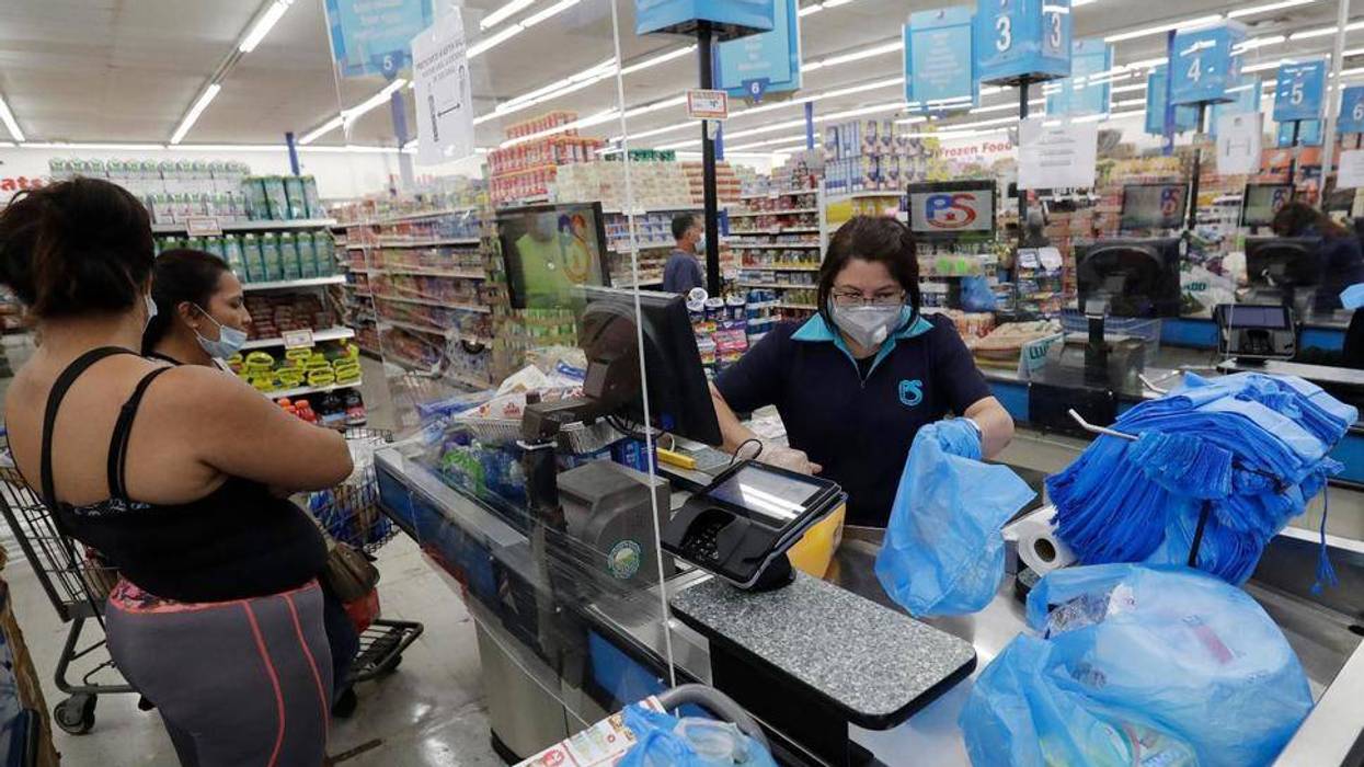 In this Wednesday, June 3, 2020 photo, cashier Rosario Vargas, center, bags groceries for customers at the Presidente Supermarket in the Little Havana neighborhood of Miami.