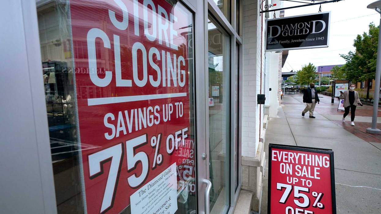 In this Wednesday, Sept. 2, 2020, file photo, passers-by walk past a business storefront with store closing and sale signs in Dedham, Mass.