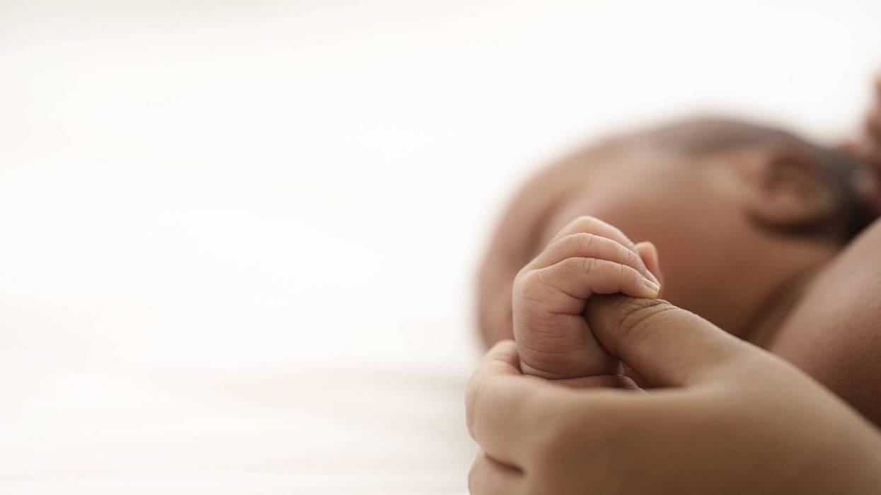 Infant baby lying on bed while mother hands pull baby up.