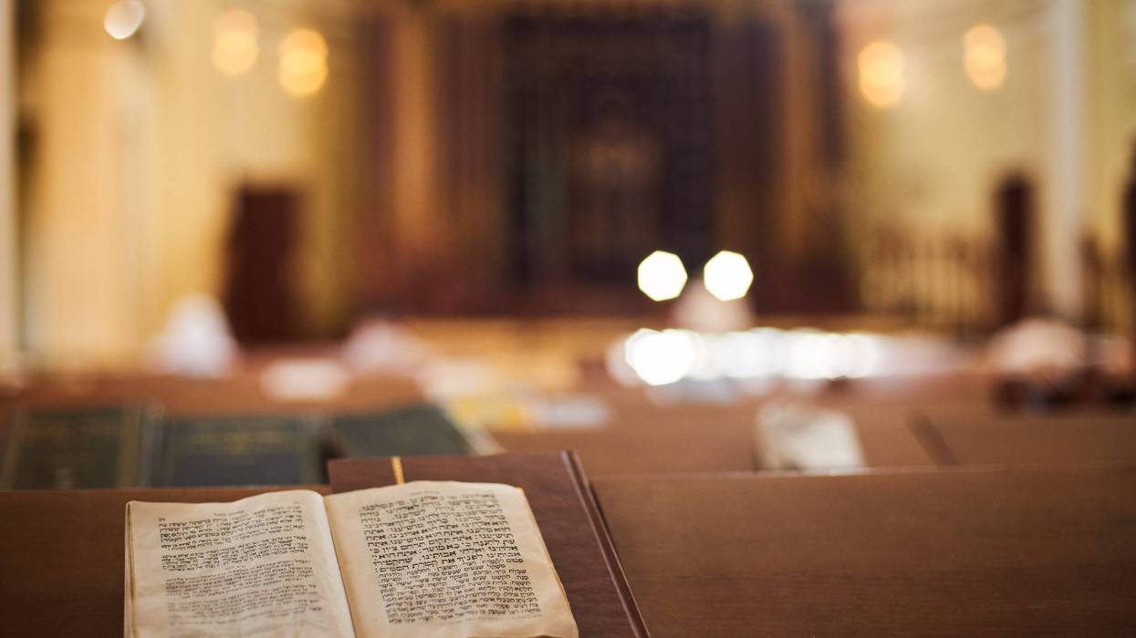 Inside of Orthodox Synagogue with open book in the Hebrew language in the foreground. selective focus.