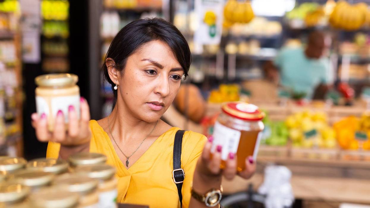 Interested woman reading product contents on jar in supermarket