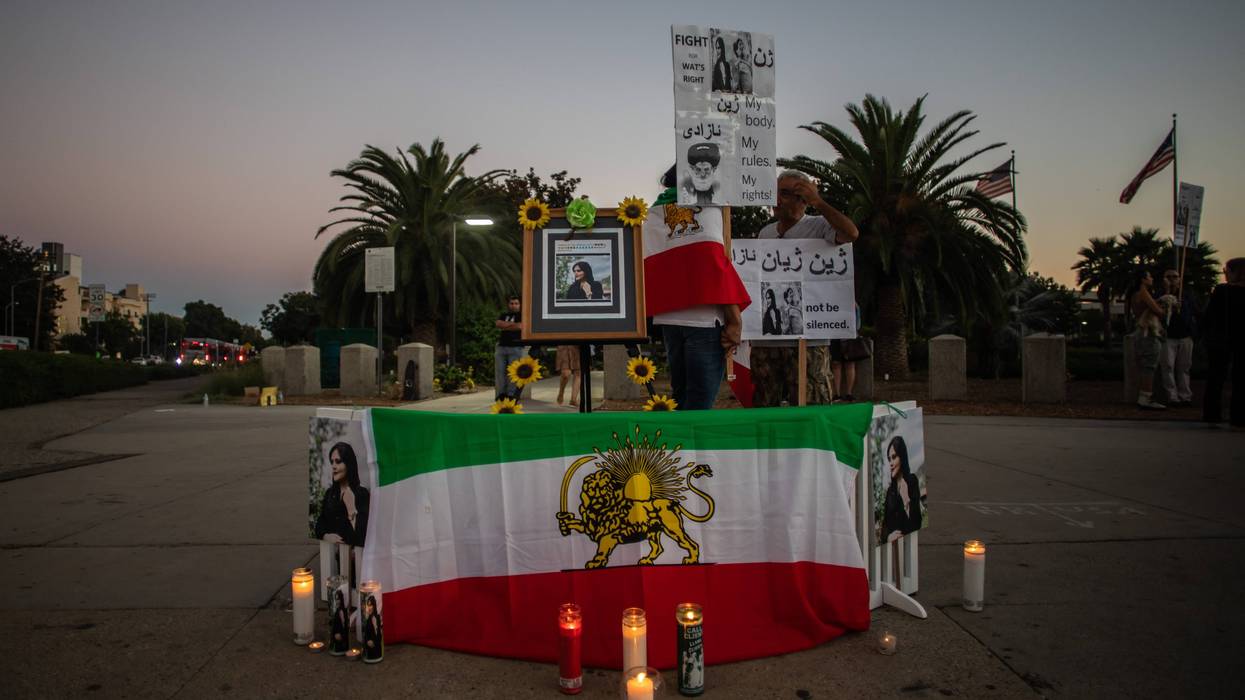 iranian flag and photos of mahsa amini with candles