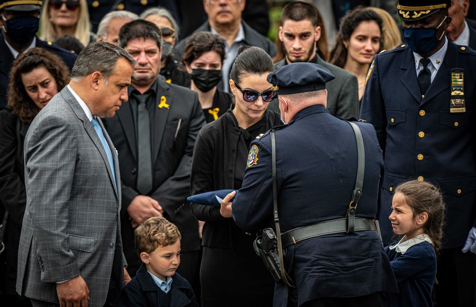 Irene Tsakos receives the flag that covered the coffin of her husband, Anastasios Tsakos, while on duty, at the closing of his service outside Saint Paraskevi Greek Orthodox Shrine Church in Greenlawn, New York on May 4, 2021