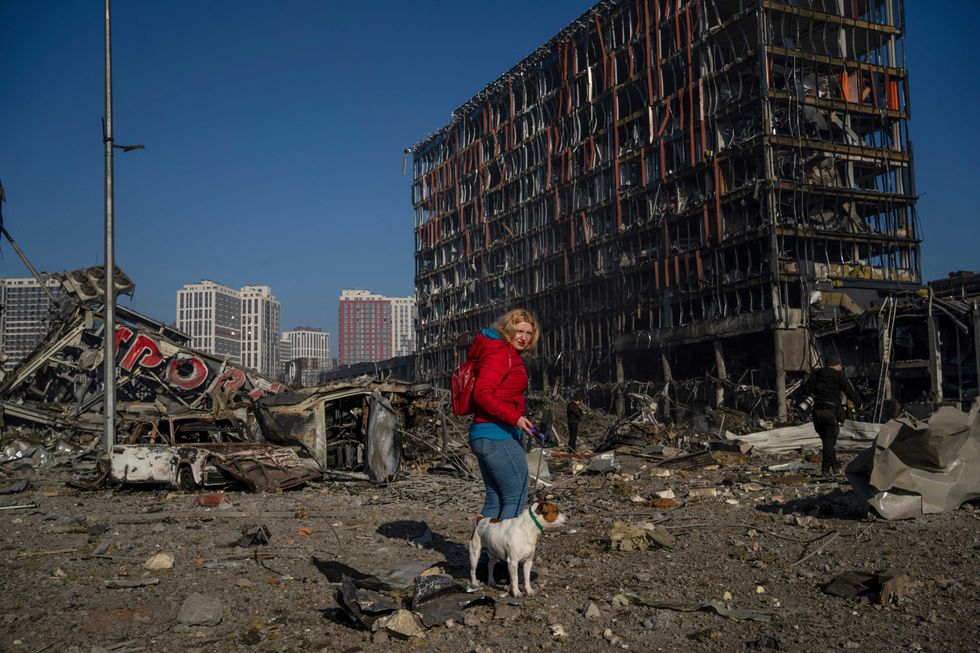 Irina Zubchenko walks with her dog Max amid the destruction caused after shelling of a shopping center, in Kyiv, Ukraine, Monday, March 21, 2022