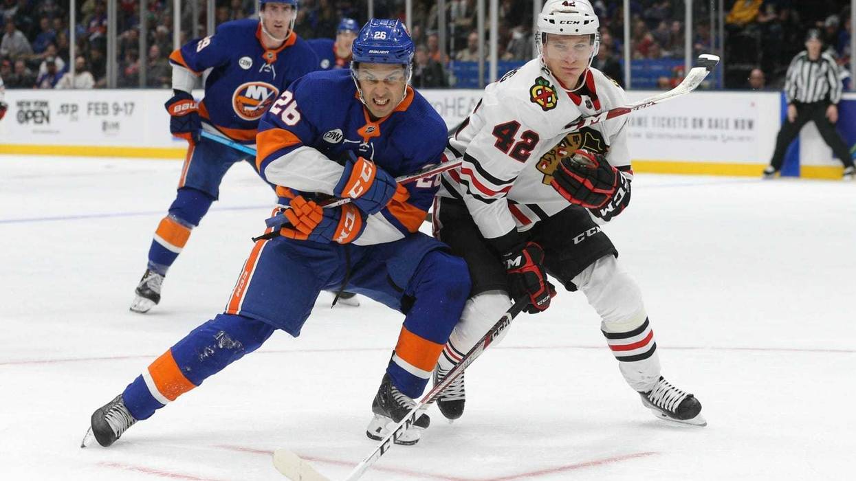 Islanders winger Josh Ho-Sang (26) and Blackhawks defenseman Gustav Forsling (42) fight for a loose puck.