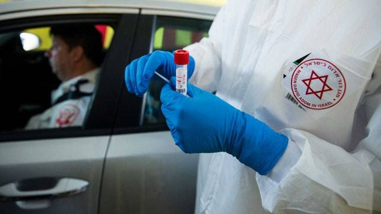 Israeli medical worker holds a swab test for coronavirus at a drive-through site during a presentation for the press before opening on March 20, 2020 in Tel Aviv, Israel.