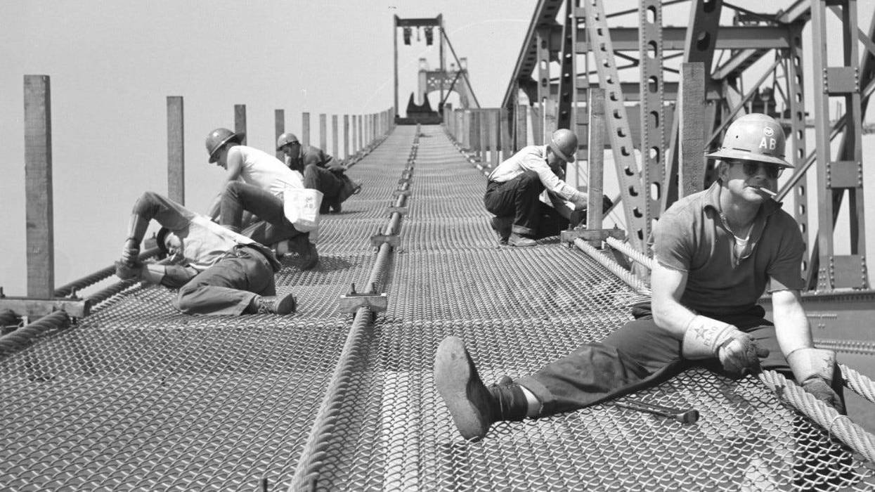 Jack R. Thompson, far right, works as part of a crew wiring the mesh to catwalk ropes between piers 17 and 18 on the Mackinac Bridge in 1956. Thompson says it was a pencil in his mouth, “not a smoke.”