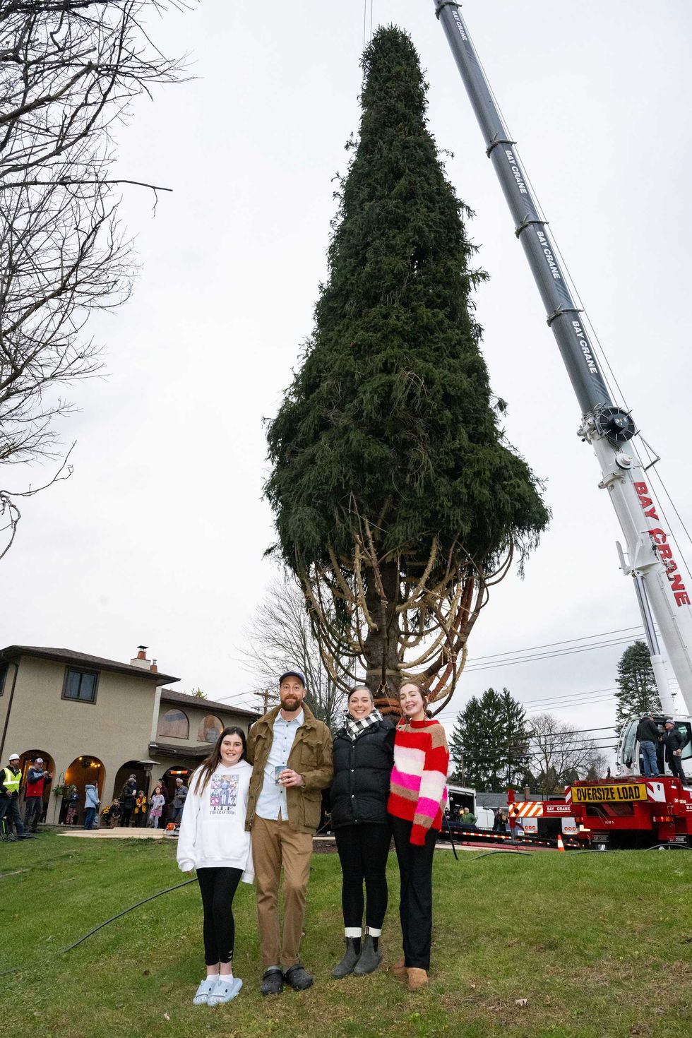 Jackie and Matt McGinley pose with their children Charlie and Zooey in front of the wrapped 80-foot tall Norway Spruce that their family donated to serve as this year